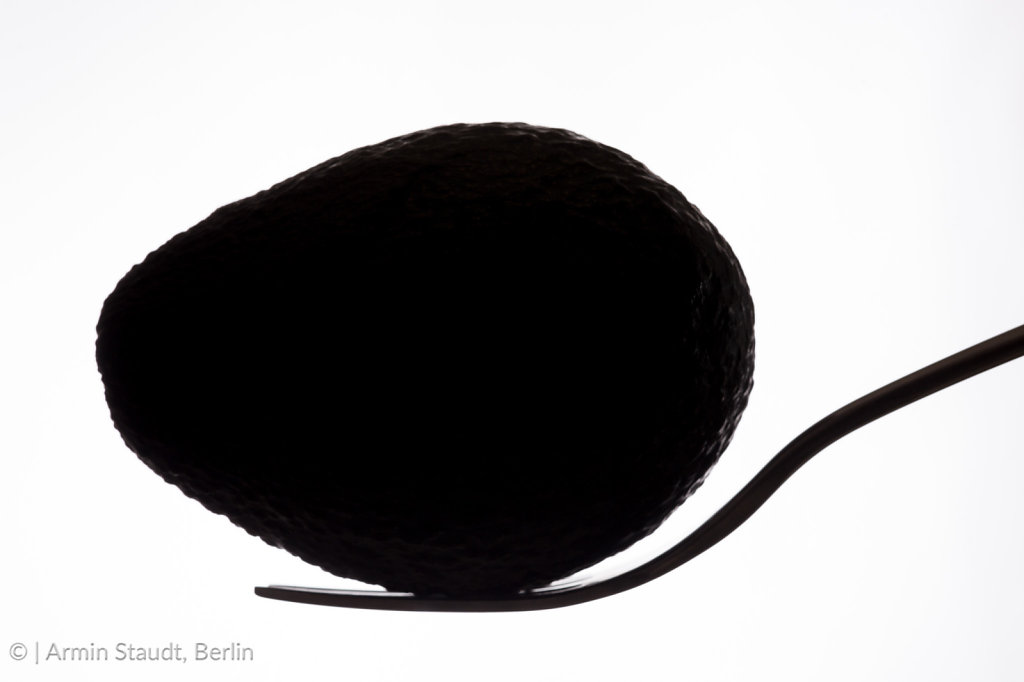 silhouette of an avocado laying on a fork, isolated on white
