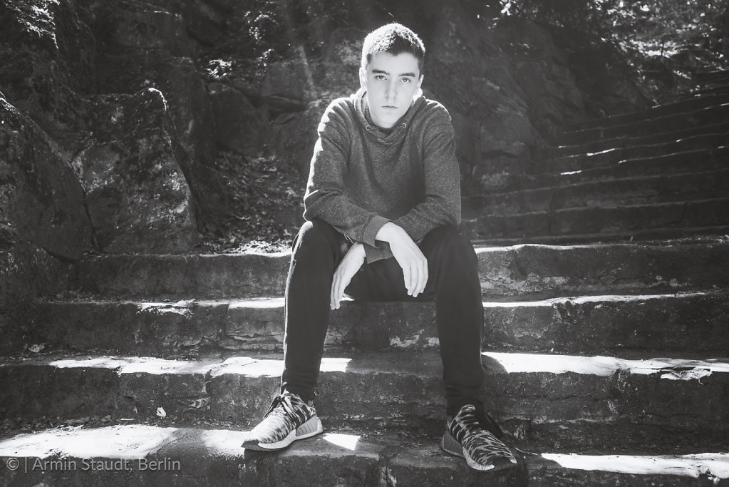 black and white portrait of a young man, sitting on stairs