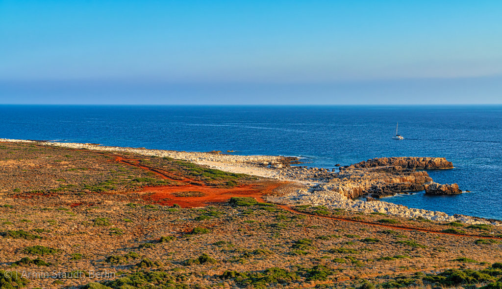mediterranean landscape with red sand, ocean an clear blue sky